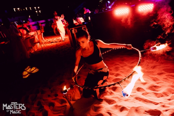 Artista donna avvolta da un cerchio di fuoco in spiaggia.